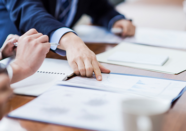 A person pointing to a group of papers sitting at a desk